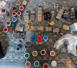 Photograph of button hardware, arrayed on a blue rug.