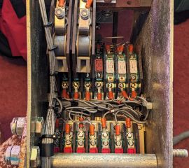 Several rows of metal contacts on top of switches, topped with screw terminals and wires